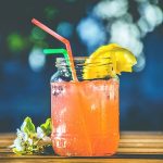 glass of sweet pink drink, with a straw and lemon