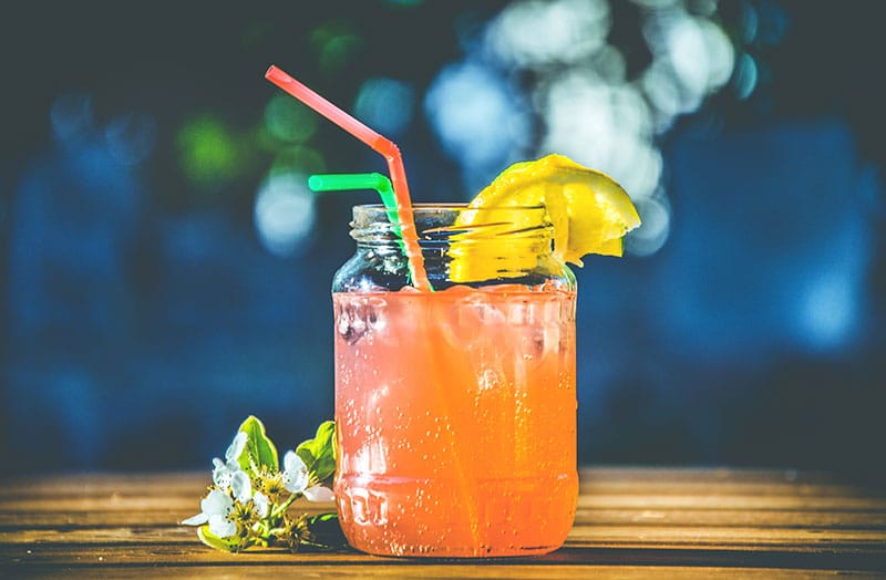 glass of sweet pink drink, with a straw and lemon