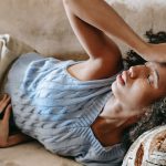 woman lying down on couch, appearing unwell