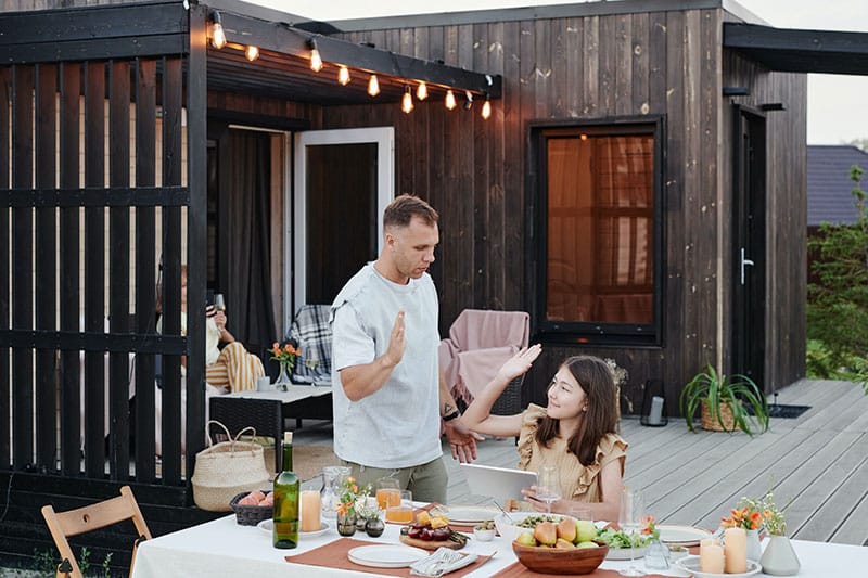 father and daughter outside, high fiving on the deck