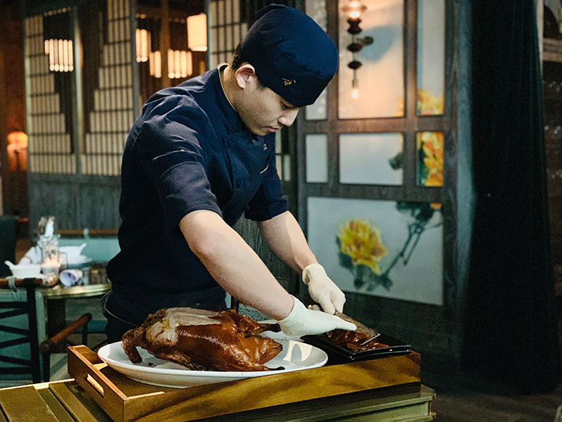 a cook carves a roasted duck in a restaraut